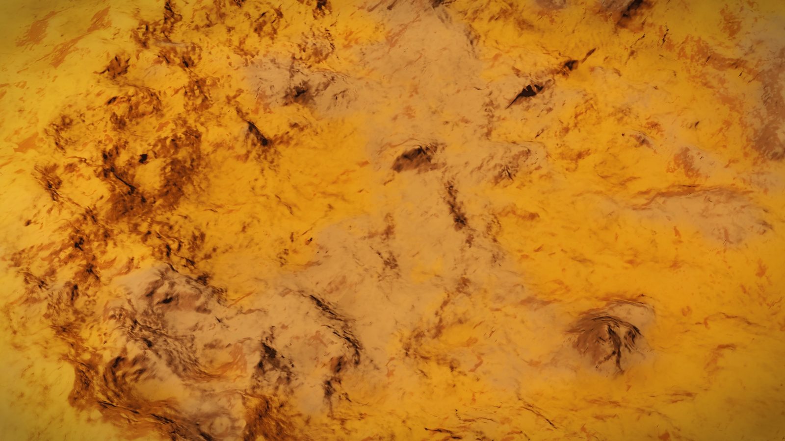 Close-up of a richly textured yellow planet surface with dark markings.